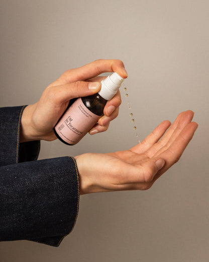 Transparante natuurlijke haarolie met rozemarijn in handpalm, verzorging voor droge hoofdhuid en haarpunten